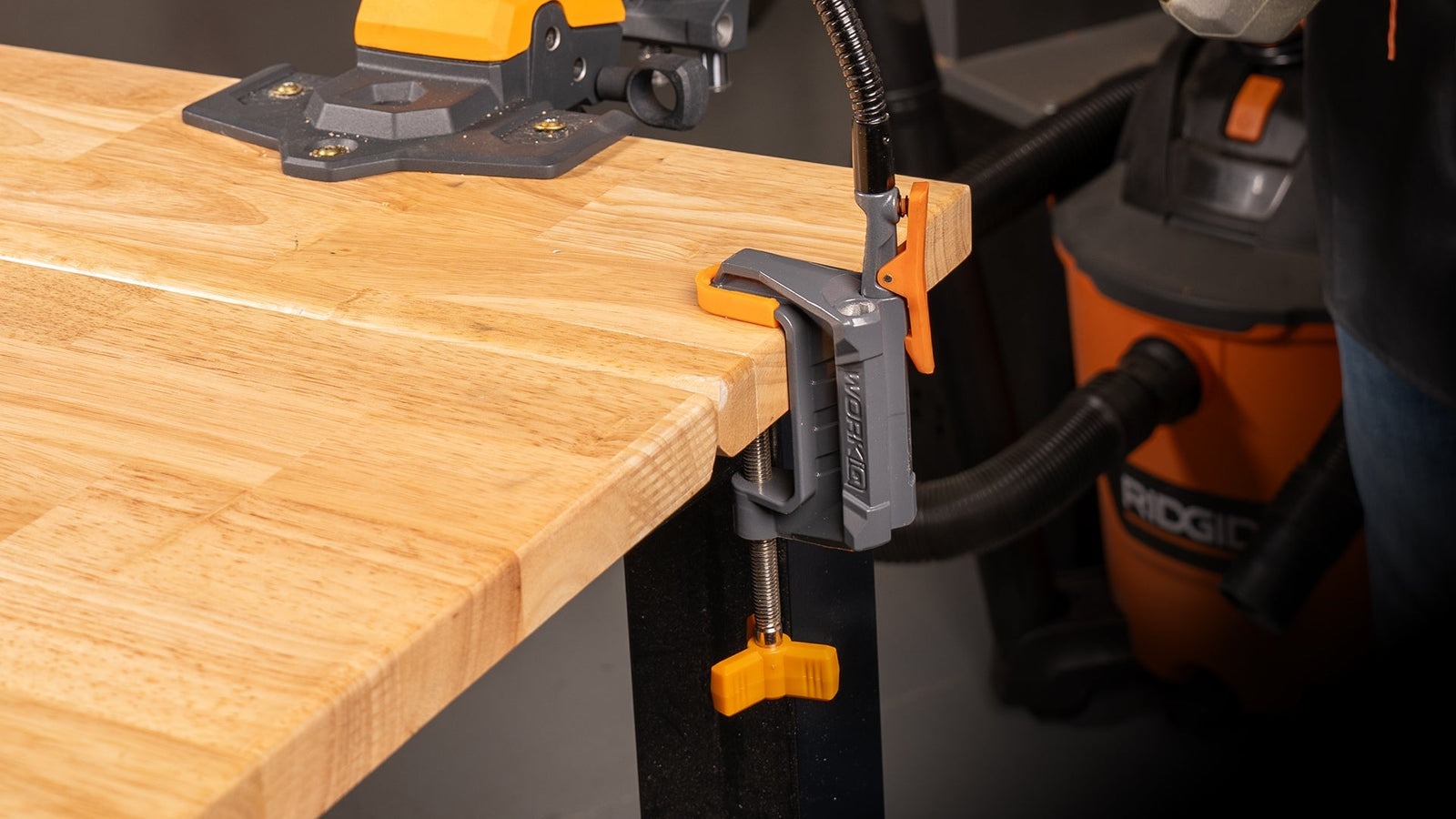 A person using an IQ Vise System to hold a piece of wood to the side of a workbench.